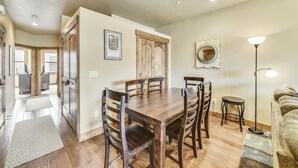 A dining area with a wooden table and chairs, a framed picture on the wall, and a floor lamp.