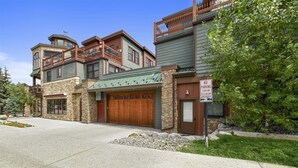 A multi-story building with a stone facade, a green roof, and a wooden garage door.