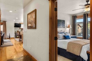 Une chambre d’hôtel avec un lit, une télévision, un tableau et une fenêtre avec des rideaux.