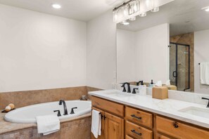 Une salle de bain moderne dotée d’une grande baignoire, d’un lavabo séparé et d’un meuble-lavabo avec des tiroirs.