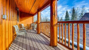 Una terraza de madera con sillas y barandilla, con vistas a un paisaje nevado.