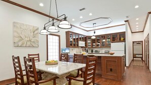 Cocina moderna con gabinetes de madera, una isla de mármol e iluminación colgante.