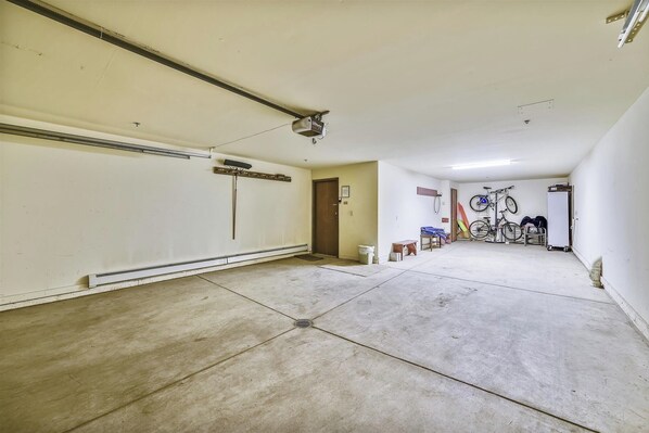 A spacious garage with a concrete floor, a door, and a ceiling with a visible duct. - Beautiful, modern condo in Marina Park in Frisco. 3 bedrooms, large, open kitchen and private 2 car garage. (Frisco)