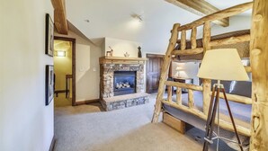 A rustic interior with a stone fireplace, wooden beams, and a ladder. - Beautiful, modern condo in Marina Park in Frisco. 3 bedrooms, large, open kitchen and private 2 car garage. (Frisco)