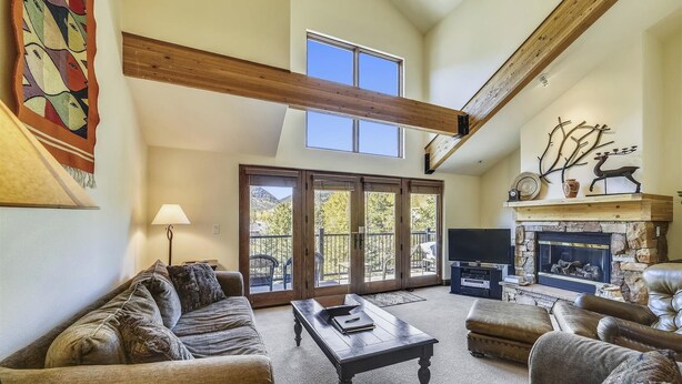 A spacious living room with a high ceiling, a fireplace, and a large sliding glass door leading to an outdoor deck. - Beautiful, modern condo in Marina Park in Frisco. 3 bedrooms, large, open kitchen and private 2 car garage. (Frisco)