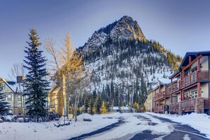 Surrounded by snow-covered peaks, this mountain lodge offers a serene retreat with a traditional facade and wooden balconies.