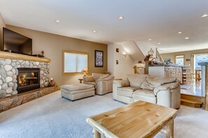 Cozy living area with a fireplace, sofa, and ottoman, offering a comfortable seating space.