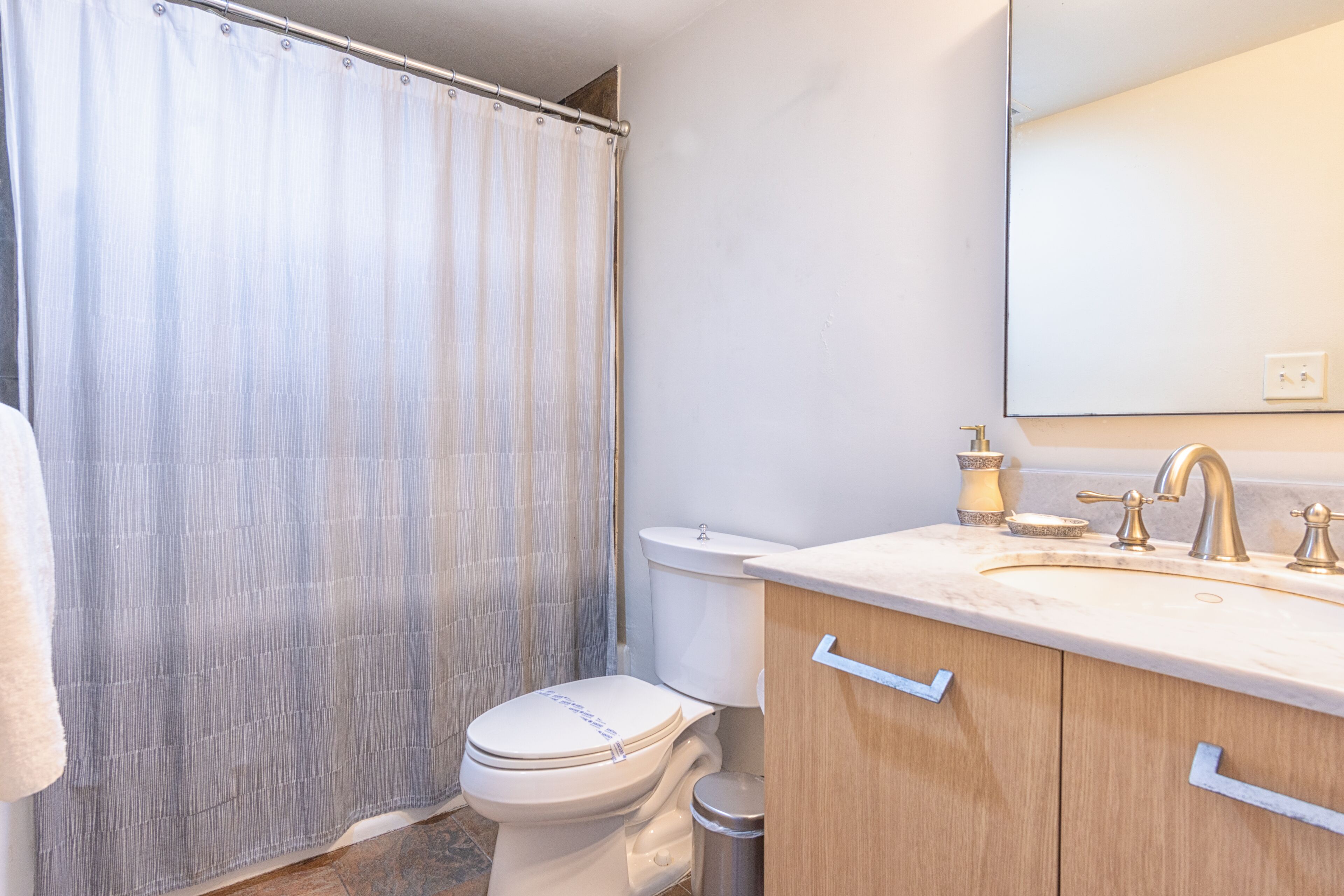 A bathroom with a toilet, sink, and mirror.