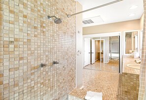 Un baño moderno con ducha empotrada, vestidor y un espejo grande.