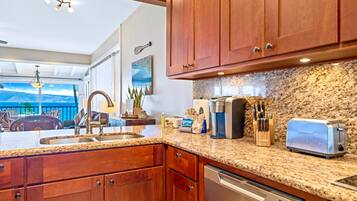 A kitchen with granite countertops, wooden cabinets, a coffee maker, a toaster, and a dishwasher.