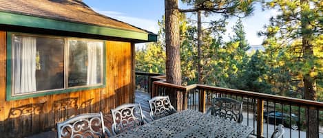 Una cabaña de madera con un porche, mobiliario exterior y vistas a árboles.
