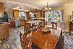 A spacious kitchen with wooden cabinets, a central island, and a dining area with a large wooden table.