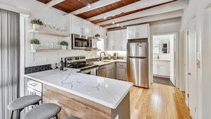 Una cocina moderna con armarios blancos, un refrigerador de acero inoxidable e una isla de mármol.