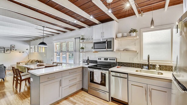Una cocina moderna con una isla central, electrodomésticos integrados y techo de madera.