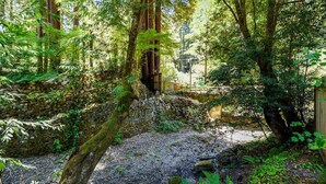 Un área boscosa con un puente de piedra y una construcción de madera.
