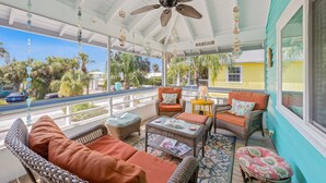 A covered outdoor area with wicker furniture, a ceiling fan, and a view of the street. - Dream Catcher- Key West style beach house on North end. (Anna Maria)