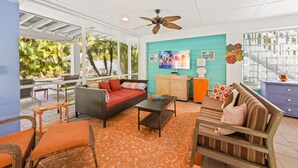 A spacious living area with a ceiling fan, a sofa set, a coffee table, and a dining area with outdoor seating. - Dream Catcher- Key West style beach house on North end. (Anna Maria)