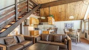 A cozy interior with a wooden staircase, a dining area with wooden chairs, and a kitchen with wooden cabinets. - Chalet #15, Charming Ski in/ Ski Out Steps to the (Mammoth Lakes)