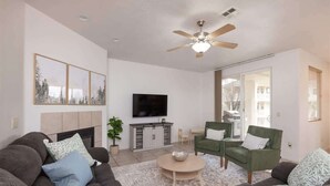 Ein Wohnzimmer mit einer Sofagarnitur, einem Couchtisch, einem Fernseher und einem Deckenventilator.
