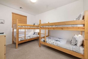 A room with two bunk beds, a wooden wardrobe, and a small desk.