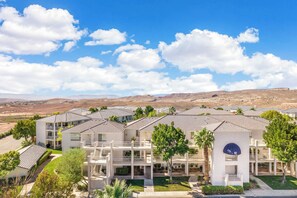 A residential complex with multiple-story buildings, a central courtyard, and a view of a mountainous landscape.