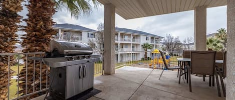 Un patio al aire libre con una parrilla, asientos y vistas de un edificio residencial.