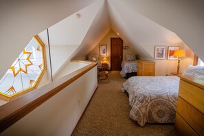 Cozy attic bedroom with a sloped ceiling, featuring two beds and a large skylight.