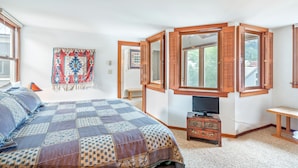 A bedroom with a large bed, a television, a wooden cabinet, and a window with shutters. - Classic Ski Condo, Steps to Chair 7 and on shuttle route (Telluride)
