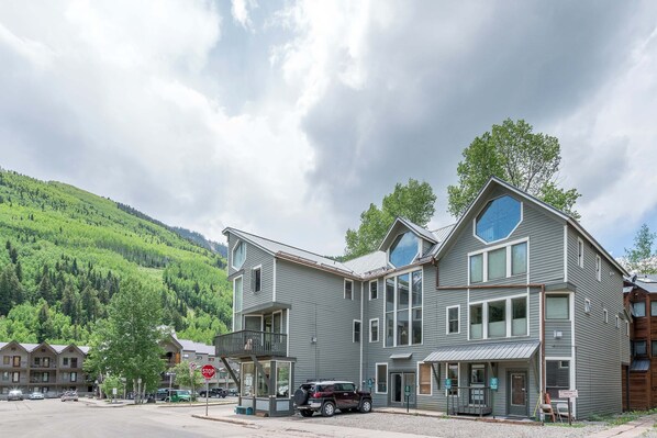 A multi-story building with a balcony, a stop sign, and a parked SUV.
