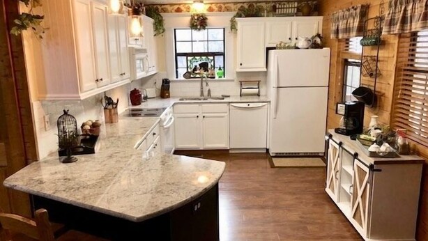 A kitchen with white cabinets, a marble countertop, and a small refrigerator.