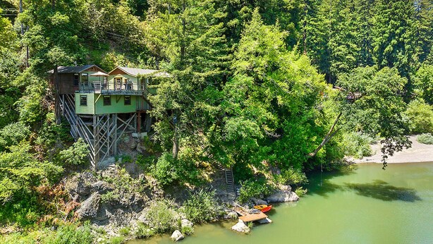 A treehouse cabin built on stilts in a forested area near a body of water. - Unwind on the River, Views, Beaches, Dog Friendly (Forestville)