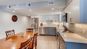 A modern kitchen with stainless steel appliances, a wooden dining table, and light-colored cabinetry. - Mountainside 2 bedroom. Only minutes from Skiing and hiking trails. (Frisco)