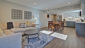 A modern living room with a sofa, coffee table, and rug. There is a dining area with a table and chairs. The kitchen has a refrigerator, stove, and cabinets. - Mountainside 2 bedroom. Only minutes from Skiing and hiking trails. (Frisco)