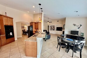 A modern kitchen with granite countertops, wooden cabinets, and a dining area with a black table and chairs.