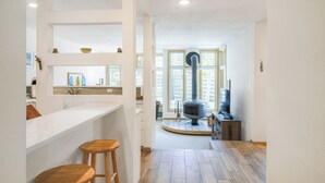 Eine moderne Küche mit weißem Arbeitsplatz, Holzstühlen und einem großen Fenster.