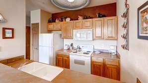 Una cocina con armarios de madera, un refrigerador blanco, una estufa y un microondas.