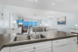 A modern kitchen with a double sink, white cabinetry, and a granite countertop.