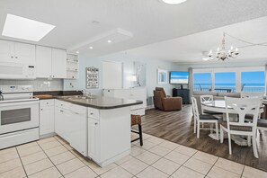 A modern kitchen with white cabinetry, a built-in oven, and a large island with a sink.