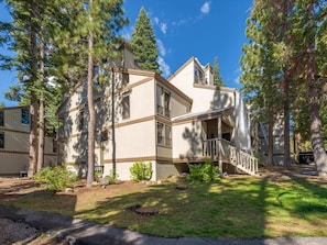 A two-story building with a balcony, surrounded by trees.