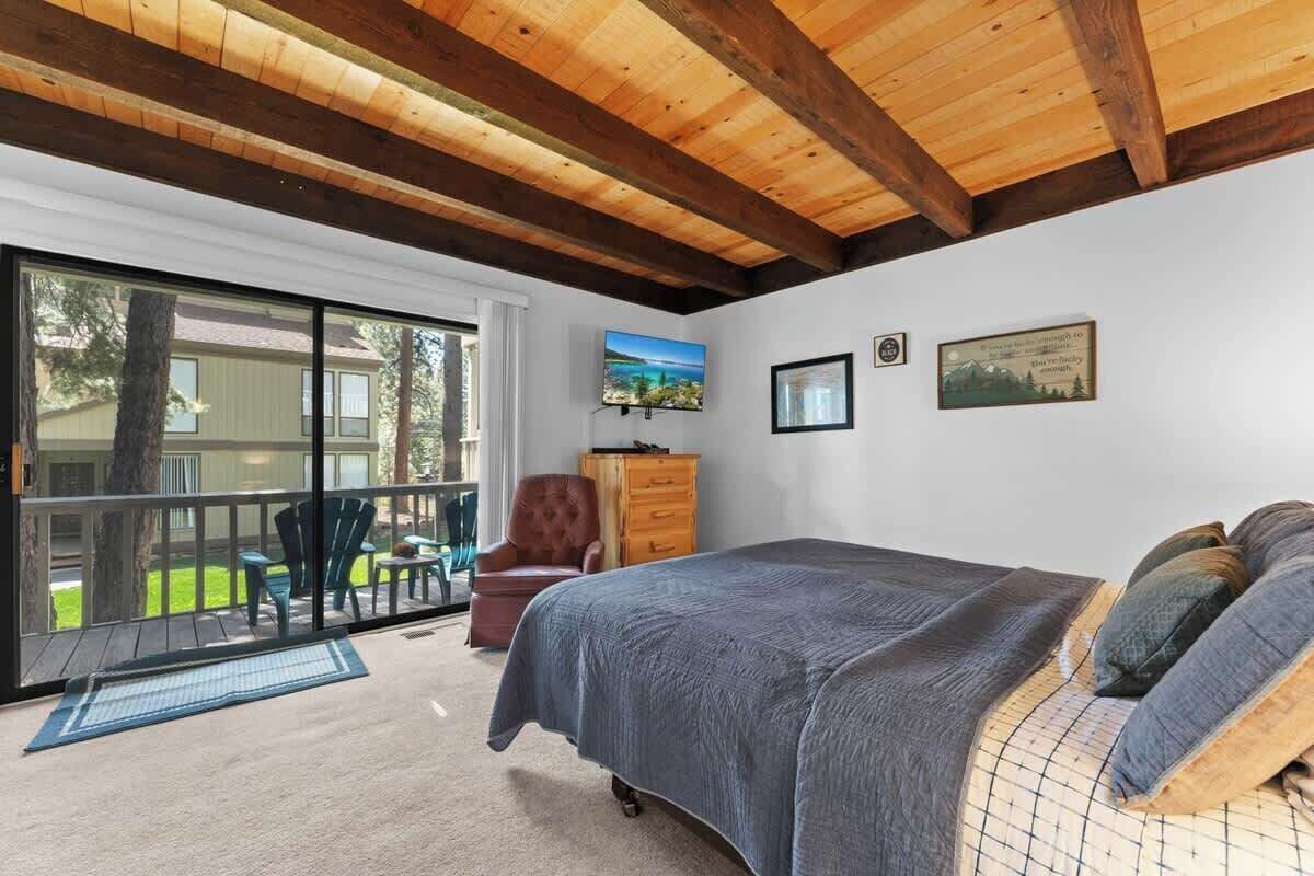 Ein Schlafzimmer mit einem großen Bett, Holzboden, einer Glastür zum Patio und einem Fernseher an der Wand.