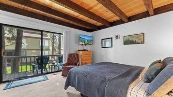Ein Schlafzimmer mit einem großen Bett, Holzboden, einer Glastür zum Patio und einem Fernseher an der Wand.