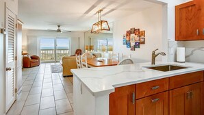 A modern kitchen with a large island, wooden cabinets, and a view to the outside. - Oceanfront Family Condo in St. Augustine (Saint Augustine)