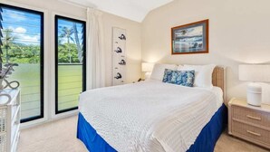 Una camera da letto con un letto, una ventola a soffitto, un comodino, una lampada e vista sull'esterno tramite una porta scorrevole.