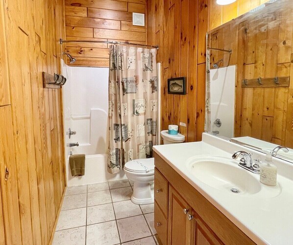 A bathroom with wooden walls, a white sink, a toilet, and a shower curtain with animal prints. - Rushing Waters - Riverfront, Hot Tub, Dog Friendly, Ping Pong Table, Gas Fireplace, WIFI (Jefferson)