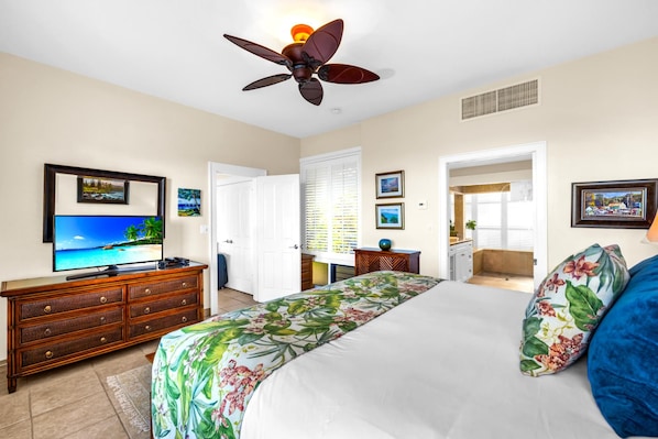 A hotel room with a bed, a television, a dresser, and a ceiling fan.