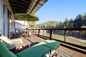 Eine Holzterrasse mit Gartenmöbeln, einem Tisch und einem grünen Sonnenschirm.