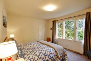 A bedroom with a bed, a bedside lamp, a window with curtains, and a door. - Riverview ~ Riverfront MCM Gem. A favorite for Family Holidays! Woof (Guerneville)