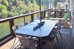 Eine Holzterrasse mit Tisch und Stühlen mit Blick auf eine bewaldete Landschaft.