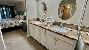 Quarto de hotel com cama de casal, duas pias, toucador com espelho e closet espaçoso.
