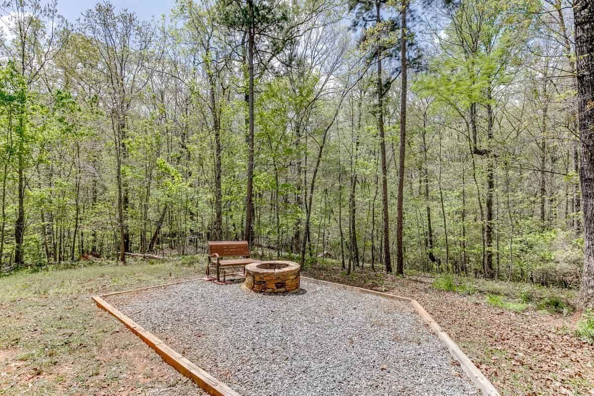 A forested campsite with a fire pit and a bench.